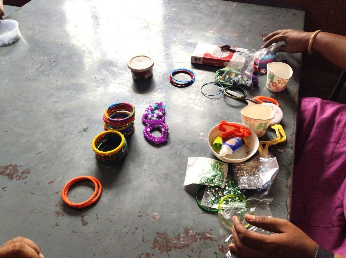 Colourful handmade bangles and bracelets laid out on a classroom table